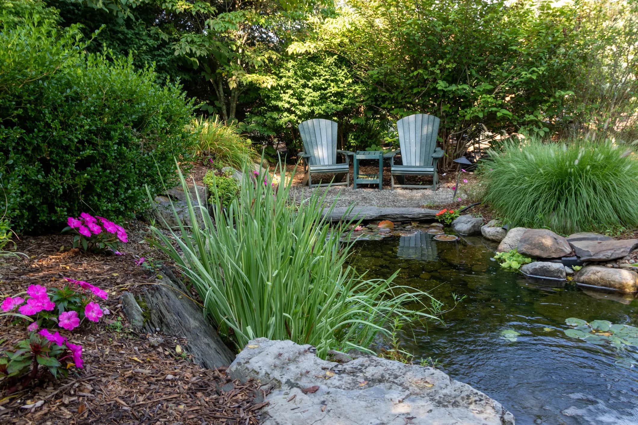 Fish Pond with chairs surrounded by greenery and flowers img for home page 